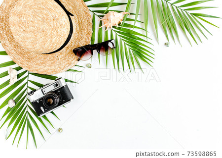 Traveler accessories, tropical palm leaf branches, straw hat on white background with empty space for text. Travel vacation concept. Traveler accessories, tropical palm leaf branches, straw hat on white background with empty space for text. Travel vacation concept. 73598865