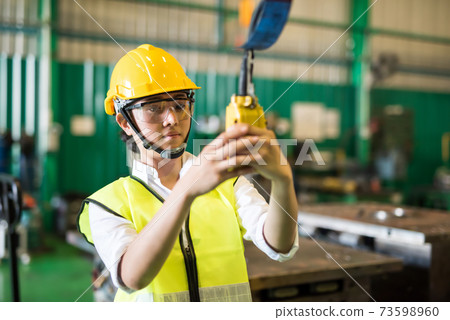 AsianfFactory worker lift crane by control panel 73598960