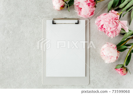 Mockup invitation, blank paper greeting card and peonies on gray stone table. Flower background. Flat lay, top view. 73599068