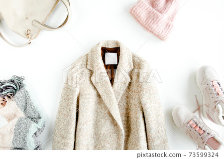 Women fashion clothes and accessories. Flat lay female autumn style look with warm coat, cap, sneakers, on white background. Top view. Women fashion clothes and accessories. Flat lay female autumn style look with warm coat, cap, sneakers, on white background. Top view. 73599324