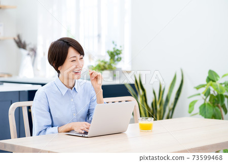 一名中年婦女在客廳里遠程辦公。 一名中年婦女在客廳里遠程辦公。 73599468
