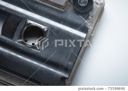 Close-up of a classic audio cassette tape with magnetic tape inside. Retro background Close-up of a classic audio cassette tape with magnetic tape inside. Retro background 73599698