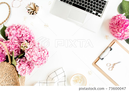 Workspace with clipboard, laptop, bouquet hydrangea, accessories on white background. Stylized women's desk. Flat lay. Top view. 73600047