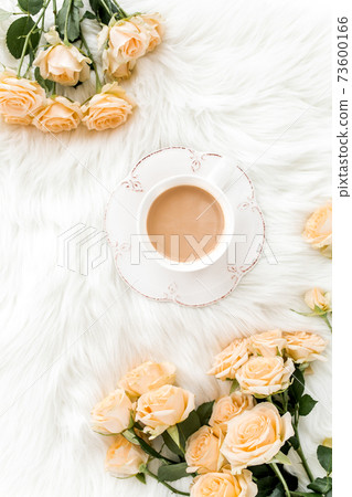 Composition of pastel tea rose bouquet flowers and a Cup of cocoa on white background. Floral background. Flat lay, top view. Composition of pastel tea rose bouquet flowers and a Cup of cocoa on white background. Floral background. Flat lay, top view. 73600166