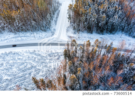 Aerial view from drone of car on curvy snow covered road in the winter forest Aerial view from drone of car on curvy snow covered road in the winter forest 73600514