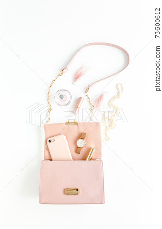 Women's pink bag with fashion trendy accessories: watch, perfume, phone, lipstick, earrings on white background. Flat lay, top view Women's pink bag with fashion trendy accessories: watch, perfume, phone, lipstick, earrings on white background. Flat lay, top view 73600612