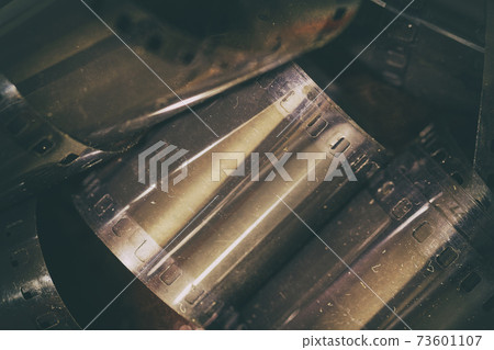 Old photographic film, dust and scratche, shallow depth of field. Photo, movie, modern cinema concept, dark background Old photographic film, dust and scratche, shallow depth of field. Photo, movie, modern cinema concept, dark background 73601107