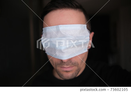 A young man puts a protective medical mask over his eyes, close-up. Doesn't want to see what's going on. during the Covid-19 pandemic on a dark blurry background. Sitina 4K A young man puts a protective medical mask over his eyes, close-up. Doesn't want to see what's going on. during the Covid-19 pandemic on a dark blurry background. Sitina 4K 73602105