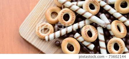 Crispy tubules, chocolate melting balls and bagels lie on a wooden surface. Mix of various sweets 73602144