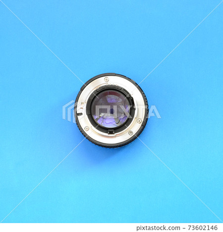 One photographic lense lie on a bright blue background. Space for text One photographic lense lie on a bright blue background. Space for text 73602146