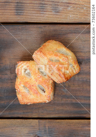 A satisfying meat patty, which combines an airy puff pastry and a delicate pork filling with onions. Baking on a wooden background A satisfying meat patty, which combines an airy puff pastry and a delicate pork filling with onions. Baking on a wooden background 73602164
