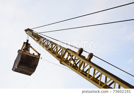 Old yellow mechanical clamshell grab on blue sky background Old yellow mechanical clamshell grab on blue sky background 73602191