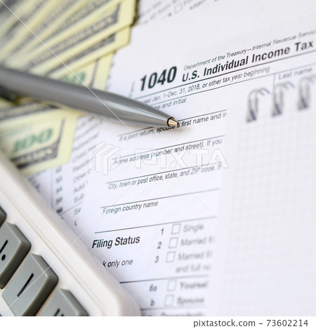 The pen, notebook, calculator, and dollar bills is lies on the tax form 1040 U.S. Individual Income Tax Return. The time to pay taxes 73602214