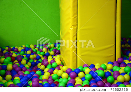 Many colorful plastic balls in a kids' ballpit at a playground 73602216