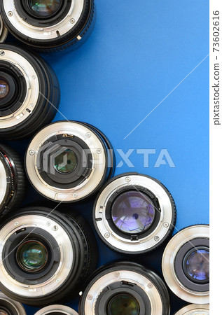 Several photographic lenses lie on a bright blue background. Space for text 73602616