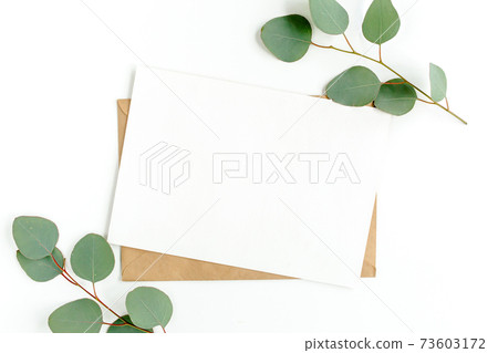 Mockup invitation, blank greeting card and green leaves eucalyptus. Flat lay, top view. 73603172