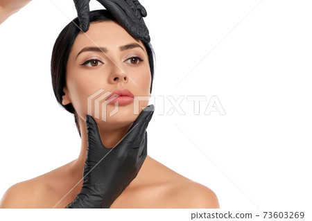 Cosmetologist in black medical gloves examining woman face Cosmetologist in black medical gloves examining woman face 73603269