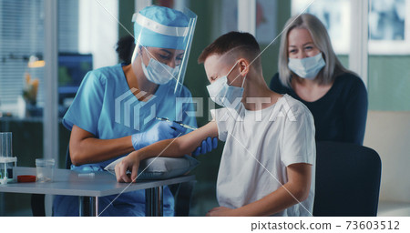 Black doctor vaccinating boy near mother 73603512