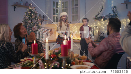 Adorable children performing poems on Christmas dinner with family Adorable children performing poems on Christmas dinner with family 73603526