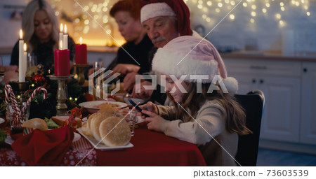 Girl addicted to phone during Christmas dinner with family Girl addicted to phone during Christmas dinner with family 73603539