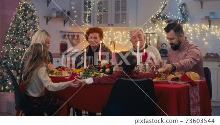 Religious family praying before Christmas dinner 73603544