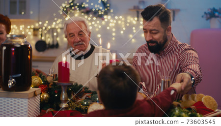 Man praying while sharing Christmas dinner with family 73603545
