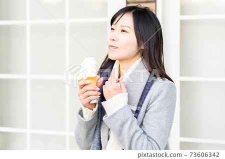 A woman eating soft serve ice cream at a tourist destination 73606342