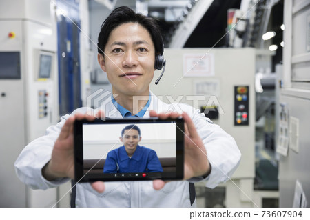 An image of a remote factory inspection by a male worker who shows the state of the factory remotely An image of a remote factory inspection by a male worker who shows the state of the factory remotely 73607904