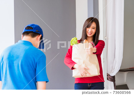 Delivery man making grocery service giving fresh vegetables in paper bag to woman customer Delivery man making grocery service giving fresh vegetables in paper bag to woman customer 73608566