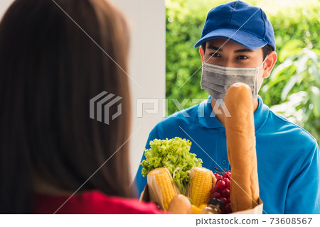 Delivery man wear protective face mask making grocery giving fresh food to woman customer Delivery man wear protective face mask making grocery giving fresh food to woman customer 73608567