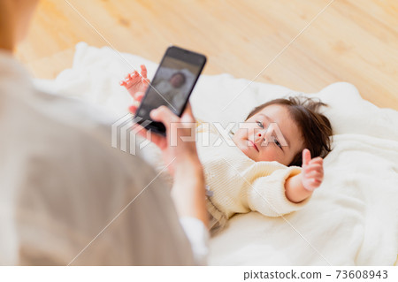 Mother taking a picture of a baby 73608943