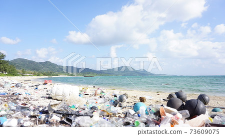 Marine plastic waste on the coastline. Plastic waste scattered around the coast contrasts with the beautiful ocean. 73609075