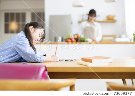 Mother watching over a child studying in the living room in the kitchen 73609377