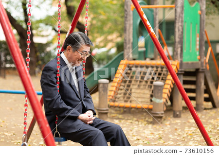 A businessman twilight on a swing in the park 73610156