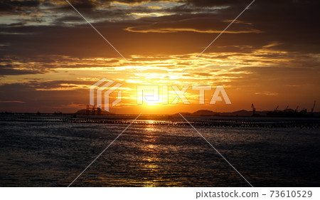 Sunset sky with silhouette of commercial dock and island 73610529