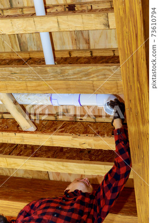 Worker using glue with fitting for installing the PVC drain pipe in the work area. Worker using glue with fitting for installing the PVC drain pipe in the work area. 73610794