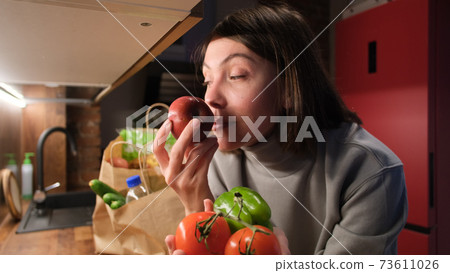 Lady smelling tomatoes and pepper 73611026