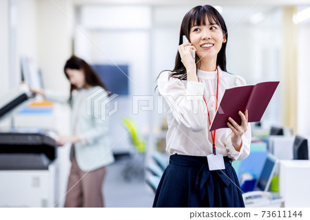Image of a woman holding a smartphone in the office 73611144
