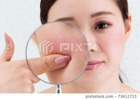 Enlarge a woman's skin with a magnifying glass. Enlarge a woman's skin with a magnifying glass. 73612723