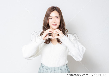 站立在白牆前面和用手做心臟形狀的一個少婦 站立在白牆前面和用手做心臟形狀的一個少婦 73614165