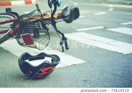 Helmet and bike lying on the road on a pedestrian crossing, after accident Helmet and bike lying on the road on a pedestrian crossing, after accident 73614519