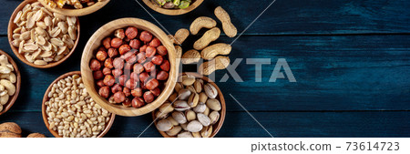 Nuts panoramic banner with a place for text. Various nuts in wooden bowls Nuts panoramic banner with a place for text. Various nuts in wooden bowls 73614723