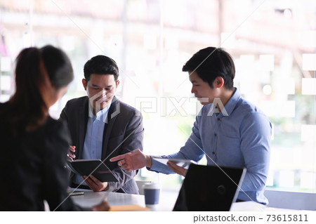 Diverse colleagues gather in modern boardroom brainstorming and discussing financial statistics together. 73615811