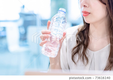 在辦公室裡喝礦泉水的女商人 73616140