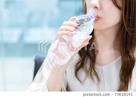 在辦公室裡喝礦泉水的女商人 73616141