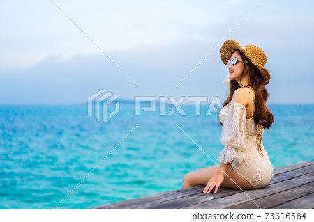 happy woman sitting on a wooden bridge in sea beach at Koh MunNork Island, Rayong, Thailand 73616584