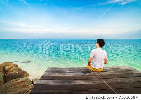 man sitting on a wooden bridge in the sea beach at Koh MunNork Island, Rayong, Thailand 73616587