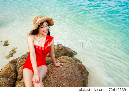 woman in swimsuit sitting on stone beach with sea at Koh MunNork Island, Rayong, Thailand woman in swimsuit sitting on stone beach with sea at Koh MunNork Island, Rayong, Thailand 73616589