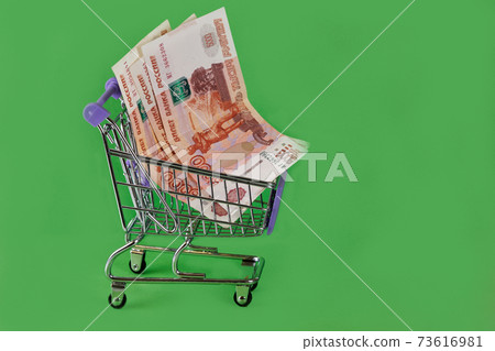 Russian banknotes in a cart from a supermarket on a green background 73616981