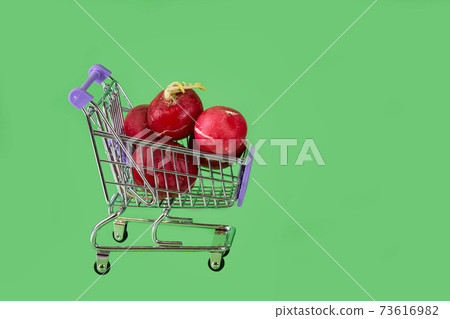 Red radish in supermarket trolley on green background 73616982